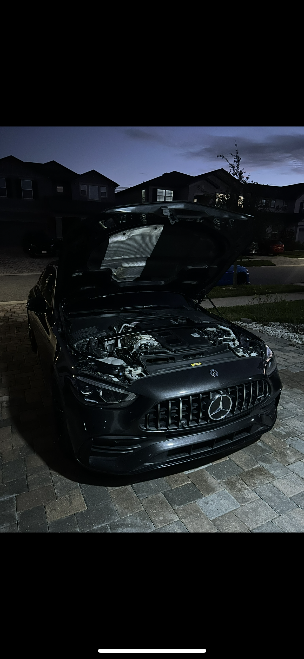 Open hood of a Mercedes-AMG sedan showing a cleaned and dressed engine bay after a cosmetic engine cleaning